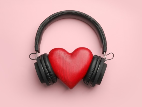 Red heart wearing black headphones against pink background