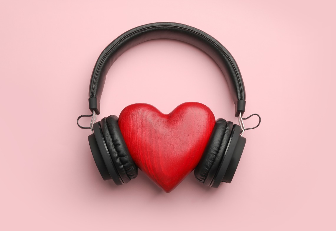 Red heart wearing black headphones against pink background