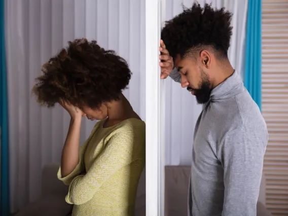 Man and woman separated by wall looking sad