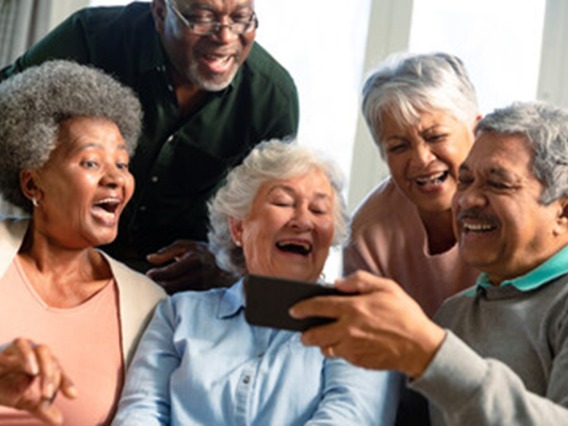 group of older adults looking at something on phone and laughing