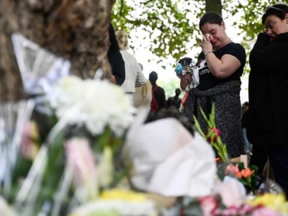 2 Women Crying & Grieving at Outdoor Daytime Memorial with Flowers
