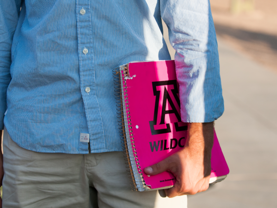 student holding pink notebook