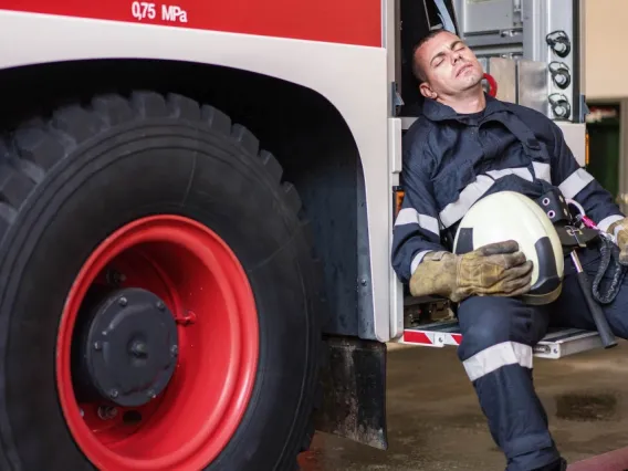 Firetruck with sleeping fireman on truck steps