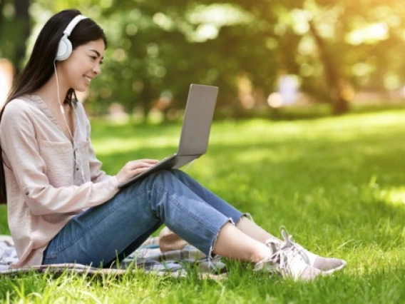 Asian woman on laptop in park
