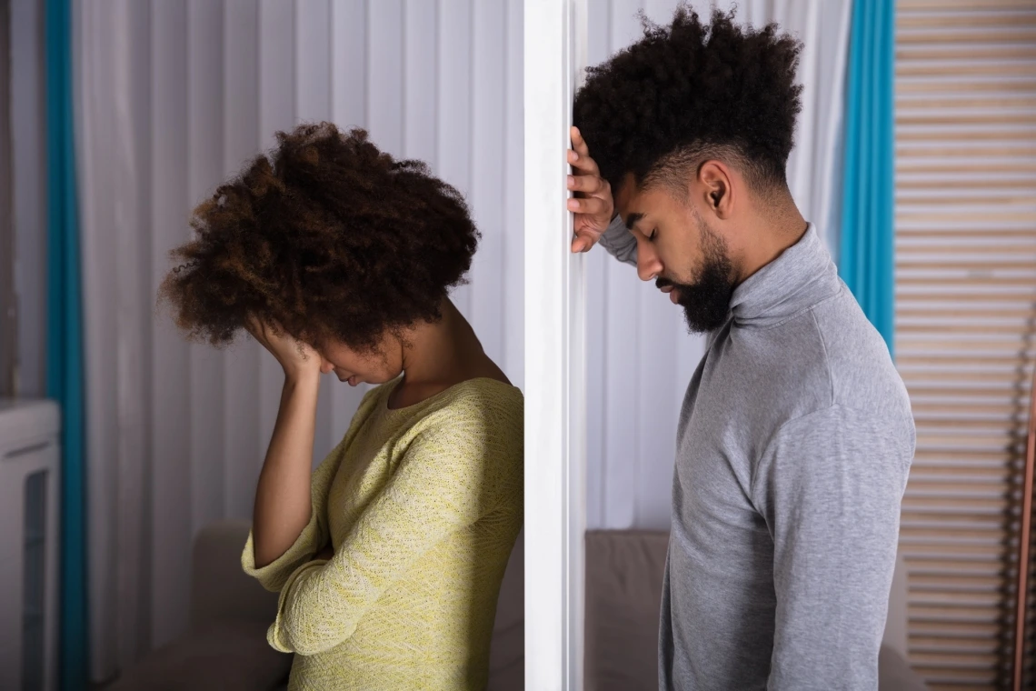 Man and woman separated by wall looking sad