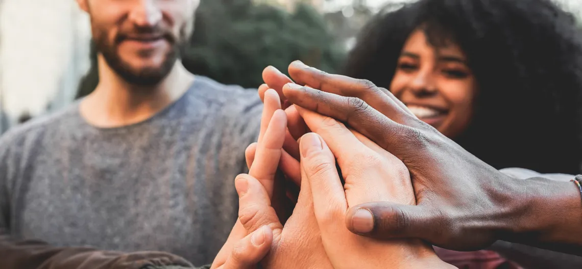 Young happy people stacking hands outdoor 