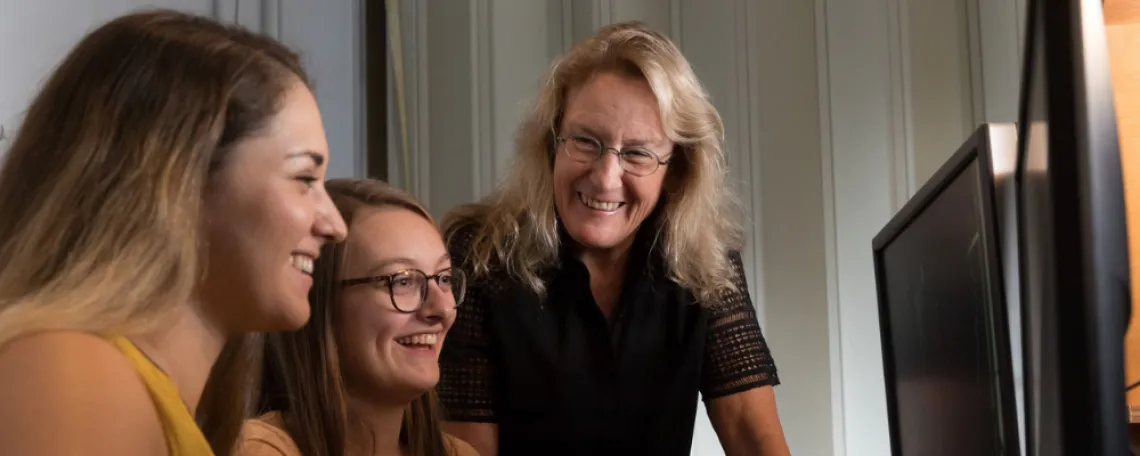 News - Barnes - Brain Research for the Ages - blonde female student, brunette female student with glasses, Carol Barnes smiling in front of computers at U of A