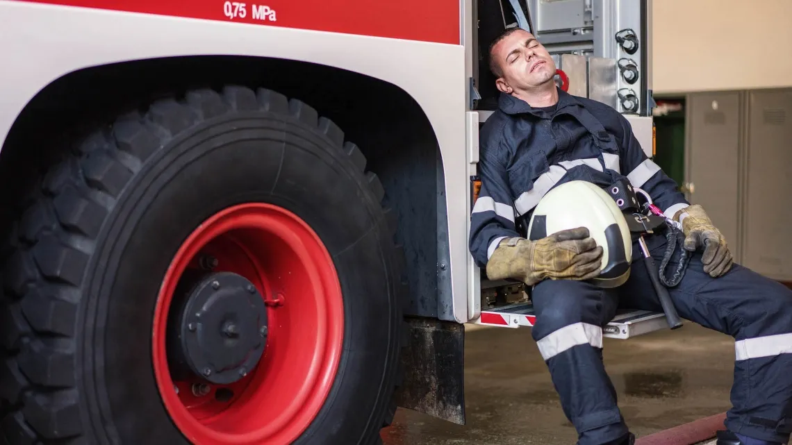 Firetruck with sleeping fireman on truck steps