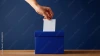 Hand depositing paper ballot into blue box